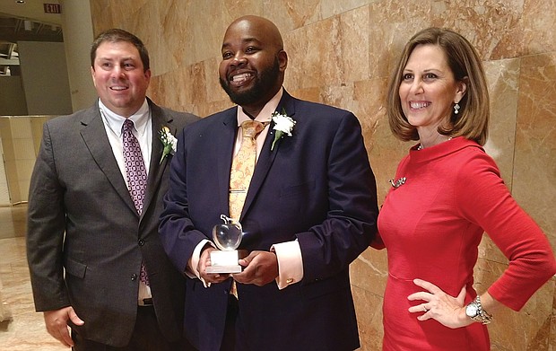 Rodney A. Robinson, the 2019 Virginia Teacher of the Year, holds the trophy he received Tuesday night at the awards ceremony at the Virginia Museum of Fine Arts. Congratulating him are Dr. James F. Lane, the state superintendent of public instruction, and Virginia First Lady Pam Northam.