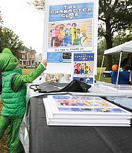 Young book lover: Lorenzo Kenup, 3, finds his power dressed as a dragon as he and his mother, Alma Kenup, peruse book offerings at the first RVA Booklovers’ Festival last Saturday in Jefferson Park. The event featured about 40 authors and poets in readings and book talks, including Joshua P. Cole, principal at Ecoff Elementary School in Chester, whose children’s book, “The Character Club,” garnered Lorenzo’s attention. Virginia First Lady Pam Northam also spoke. Proceeds from the event were to benefit local literacy organizations. (Regina H. Boone/Richmond Free Press)