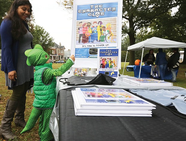 Young book lover: Lorenzo Kenup, 3, finds his power dressed as a dragon as he and his mother, Alma Kenup, peruse book offerings at the first RVA Booklovers’ Festival last Saturday in Jefferson Park. The event featured about 40 authors and poets in readings and book talks, including Joshua P. Cole, principal at Ecoff Elementary School in Chester, whose children’s book, “The Character Club,” garnered Lorenzo’s attention. Virginia First Lady Pam Northam also spoke. Proceeds from the event were to benefit local literacy organizations. (Regina H. Boone/Richmond Free Press)