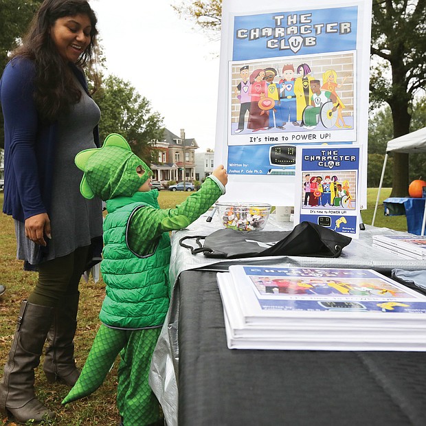 Young book lover: Lorenzo Kenup, 3, finds his power dressed as a dragon as he and his mother, Alma Kenup, peruse book offerings at the first RVA Booklovers’ Festival last Saturday in Jefferson Park. The event featured about 40 authors and poets in readings and book talks, including Joshua P. Cole, principal at Ecoff Elementary School in Chester, whose children’s book, “The Character Club,” garnered Lorenzo’s attention. Virginia First Lady Pam Northam also spoke. Proceeds from the event were to benefit local literacy organizations. (Regina H. Boone/Richmond Free Press)