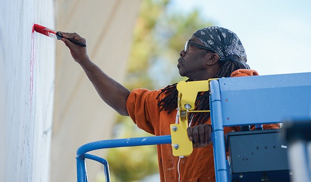 Artists Mee-Mee Caston and Sir James Thornhill begin painting a new mural on a concrete wall that faces Martin Luther King Jr. Middle School on Mosby Street in the East End. A volunteer team of about 10 students participated in designing the new tribute to Dr. King and also will take part in the painting, Mr. Thornhill said. (Photo by Clement Britt)