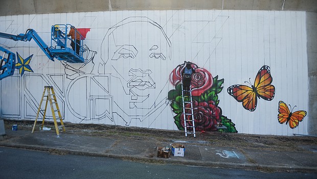 Artists Mee-Mee Caston and Sir James Thornhill begin painting a new mural on a concrete wall that faces Martin Luther King Jr. Middle School on Mosby Street in the East End. A volunteer team of about 10 students participated in designing the new tribute to Dr. King and also will take part in the painting, Mr. Thornhill said. (Photo by Clement Britt)