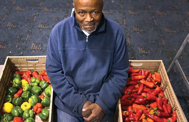 Charles E. Fitzgerald shows off a bounty of fresh peppers that he and other Atlee Church volunteers had ready for distribution at the Moss Side Avenue church last Saturday.