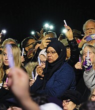 Hundreds of people of different faiths, races and backgrounds raise lights of hope at the end of Tuesday night’s vigil at the Weinstein Jewish Community Center on Monument Avenue.
