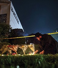 Rabbi Eli Wilansky lights a candle outside the Tree of Life Synagogue in Pittsburgh’s Squirrel Hill neighborhood on Saturday night following a deadly mass shooting at the temple. Memorial flowers and candles lined the site, despite the yellow police crime scene tape.
