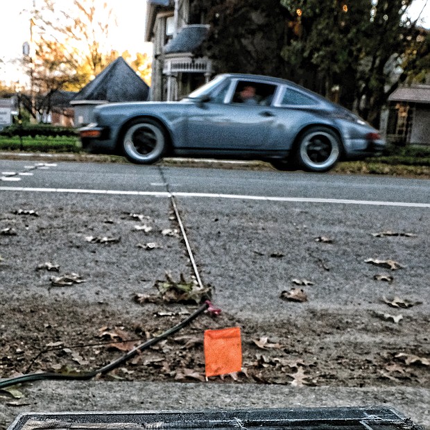 By driving over the black rubber tubing across the roadway, this car adds to the count of vehicles using this street on Monday in Richmond’s Museum District. Location: 2900 block of Grove Avenue. Collecting accurate data on the number of vehicles using a roadway is part of the work of the Virginia Department of Transportation, which regularly sets out counters and the connecting tubing on streets and roads across the state. (Sandra Sellars/Richmond Free Press)