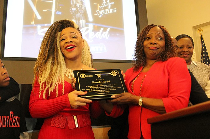 Sandy Redd (left) display her key to the village after receiving it from Mayor Shelia Chalmers-Currin at  a recent community event in Matteson