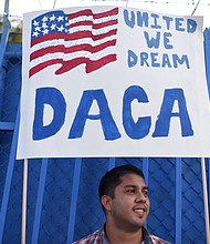 DACA recipient and appliance repair business owner Erick Marquez holds a sign during a protest in support of DACA, September 10, 2017, in Los Angeles.