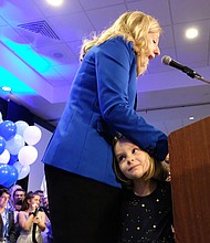 Abigail Spanberger speaks to the crowd Tuesday night as her daughter Catherine, 4, peeks out at the crowd.