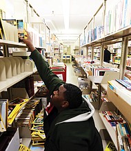 Stretching to learn : Clyde Ferguson III of Chesterfield reaches for the National Geographic magazines on a top shelf as he peruses the issues available last Saturday at the semiannual book sale sponsored by the Friends of the Richmond Public Library. The two-day event held at the Main Library at 101 E. Franklin St. draws voracious readers who patiently comb the stacks and boxes of books, magazines, CDs and other materials to select and purchase their latest treasures. (Regina H. Boone/Richmond Free Press)