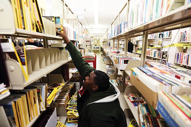 Stretching to learn : Clyde Ferguson III of Chesterfield reaches for the National Geographic magazines on a top shelf as he peruses the issues available last Saturday at the semiannual book sale sponsored by the Friends of the Richmond Public Library. The two-day event held at the Main Library at 101 E. Franklin St. draws voracious readers who patiently comb the stacks and boxes of books, magazines, CDs and other materials to select and purchase their latest treasures. (Regina H. Boone/Richmond Free Press)
