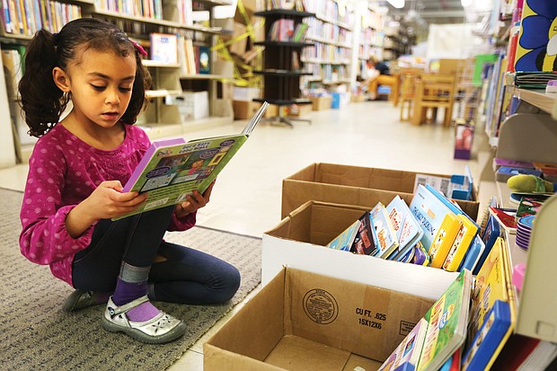 Leonora Wiziarde, 6, of Richmond is a voracious reader and what better place to read than the children's section of the Friends of the Richmond Public Library Book Sale Saturday, Nov. 3, 2018, held at the Main Library at 101 E. Franklin St. (Regina H. Boone/Richmond Free Press)