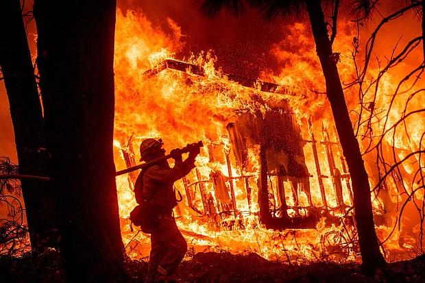 Firefighter Jose Corona sprays water as flames consume a home in Magalia, California