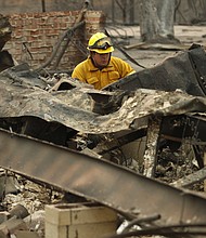 A firefighter looks through a destroyed home in Paradise.