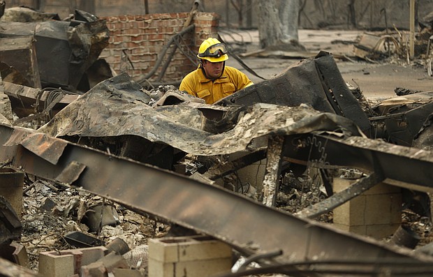 A firefighter looks through a destroyed home in Paradise.