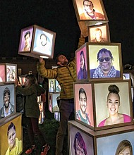 A variety of innovative art pieces adorn the grounds of the Virginia Museum of Fine Arts’ Sculpture Garden during InLight Richmond, the 11th annual light-based show of art and performances sponsored by the 1708 Gallery last weekend. Luke Hostetler participates in Kevin Orlosky’s installation, “Building Together,” while faces are visible. (James Haskins/Richmond Free Press)
