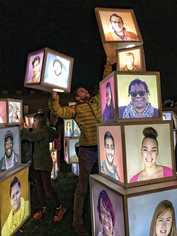 A variety of innovative art pieces adorn the grounds of the Virginia Museum of Fine Arts’ Sculpture Garden during InLight Richmond, the 11th annual light-based show of art and performances sponsored by the 1708 Gallery last weekend. Luke Hostetler participates in Kevin Orlosky’s installation, “Building Together,” while faces are visible. (James Haskins/Richmond Free Press)