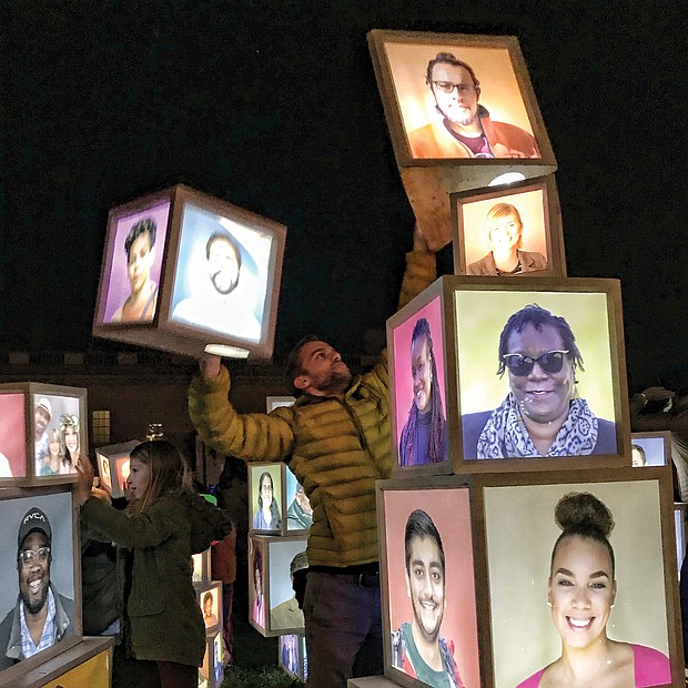 A variety of innovative art pieces adorn the grounds of the Virginia Museum of Fine Arts’ Sculpture Garden during InLight Richmond, the 11th annual light-based show of art and performances sponsored by the 1708 Gallery last weekend. Luke Hostetler participates in Kevin Orlosky’s installation, “Building Together,” while faces are visible. (James Haskins/Richmond Free Press)