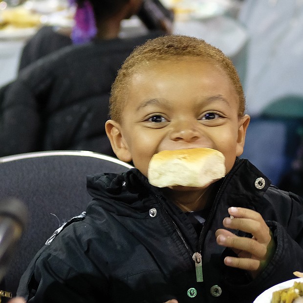Delicious! Jabriel Birchett, 5, takes a bite of his roll on Thanksgiving Day and doesn’t want to let go. The youngster was enjoying good food with family at The Giving Heart Community Thanksgiving Feast at the Greater Richmond Convention Center in Downtown. (Sandra Sellars/Richmond Free Press)