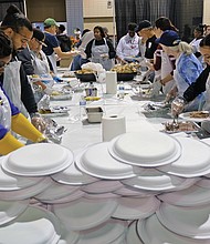 Giving thanks: Hundreds of people enjoyed a sumptuous dinner on Thanksgiving Day at The Giving Heart Community Thanksgiving Feast at the Greater Richmond Convention Center in Downtown. The annual event is free and draws hundreds of volunteers and contributors who provide fellowship and service to families and individuals sitting down for dinner. Behind the scenes, volunteers are hard at work preparing plates with turkey and all the fixings. (Sandra Sellars/Richmond Free Press)