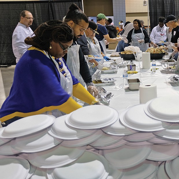 Giving thanks: Hundreds of people enjoyed a sumptuous dinner on Thanksgiving Day at The Giving Heart Community Thanksgiving Feast at the Greater Richmond Convention Center in Downtown. The annual event is free and draws hundreds of volunteers and contributors who provide fellowship and service to families and individuals sitting down for dinner. Behind the scenes, volunteers are hard at work preparing plates with turkey and all the fixings. (Sandra Sellars/Richmond Free Press)