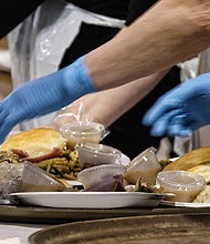 Giving thanks: Hundreds of people enjoyed a sumptuous dinner on Thanksgiving Day at The Giving Heart Community Thanksgiving Feast at the Greater Richmond Convention Center in Downtown. The annual event is free and draws hundreds of volunteers and contributors who provide fellowship and service to families and individuals sitting down for dinner. Behind the scenes, volunteers are hard at work preparing plates with turkey and all the fixings. (Sandra Sellars/Richmond Free Press)