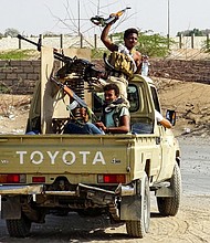 Pro-government forces cheer in the back of a pickup mounted with a machine gun outside Hodeidah.