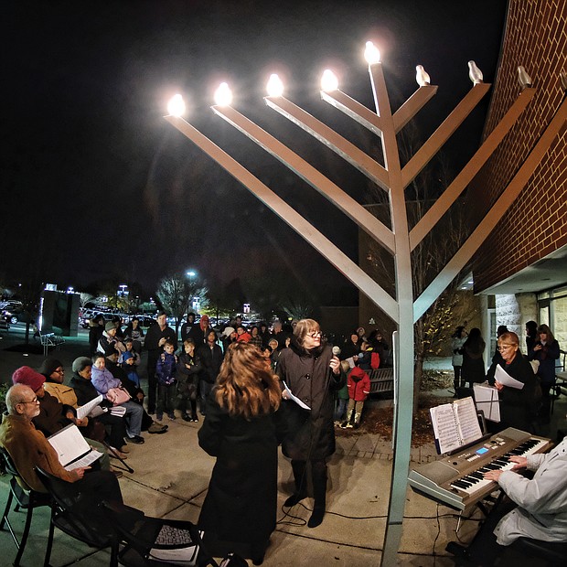 Celebrating Hanukkah: Dozens of people gather at the Weinstein Jewish Community Center in Richmond on Wednesday for the lighting of the menorah for Hanukkah. The eight-day Jewish festival of lights, which began Sunday night, commemorates the re-dedication of the Temple in Jerusalem by the Maccabees after their victory over Antiochus, who outlawed Judaism in 167 B.C. To celebrate their victory, the Jewish people tried to carry out a ritual lighting of a menorah in the temple, but found only enough oil to light it for one day. However, the oil miraculously lasted for eight days. Traditional foods and gifts are part of the religious holiday that ends Monday, Dec. 10. (Sandra Sellars/Richmond Free Press)