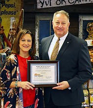 Telesha Bertrand (left), Louisiana Fur & Wildlife Festival president, receives the Southeast Tourism Society Top 20 Event award from Sam Wilkinson (right), chairman of the board of directors of the Lake Charles/Southwest Louisiana Convention & Visitors Bureau.