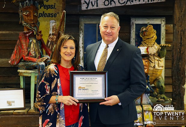 Telesha Bertrand (left), Louisiana Fur & Wildlife Festival president, receives the Southeast Tourism Society Top 20 Event award from Sam Wilkinson (right), chairman of the board of directors of the Lake Charles/Southwest Louisiana Convention & Visitors Bureau.