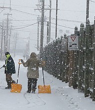 Brrrrr! The first snowfall of the season last Sunday resulted in people heading outdoors in the cold to clear snowy walkways and parking spots so that people and cars could safely maneuver. Two restaurant employees in Scott’s Addition try to stay ahead of the falling flakes by shoveling and salting a sidewalk. (Regina H. Boone/Richmond Free Press)