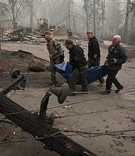 Yuba and Butte County sherriff deputies carry a body bag with a deceased victim of the Camp Fire on November 10, 2018 in Paradise, California.