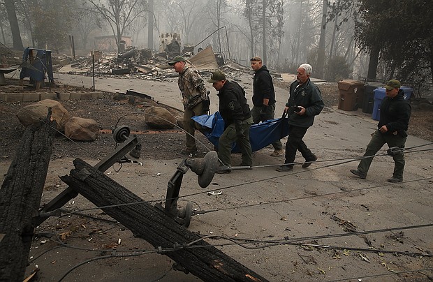 Yuba and Butte County sherriff deputies carry a body bag with a deceased victim of the Camp Fire on November 10, 2018 in Paradise, California.