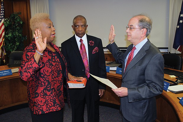 Richmond School Board member Cheryl L. Burke takes the oath of office Tuesday at City Hall while her husband, Emmitt Burke, holds the Bible. Administering the oath of office is Richmond Circuit Court Clerk Edward F. Jewett.