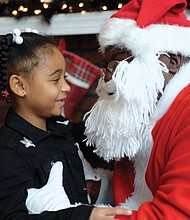 Leave it to Santa: Skye Cook, 6, tells all her Christmas wishes to Soul Santa during a recent visit to the Black History Museum & Cultural Center of Virginia in Jackson Ward. Soul Santa is always a big hit at the museum on December weekends leading up to the holiday. In just a few days, the youngster will see if Santa truly delivered. (Sandra Sellars/Richmond Free Press)