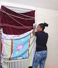 Kanya N. Nash puts blankets and quilts up at the windows to stave off January’s cold in her apartment in the Hillside Court public housing community. She was among hundreds of public housing residents impacted by poor maintenance and the replacement of failed heating systems in buildings run by the Richmond Redevelopment and Housing Authority.