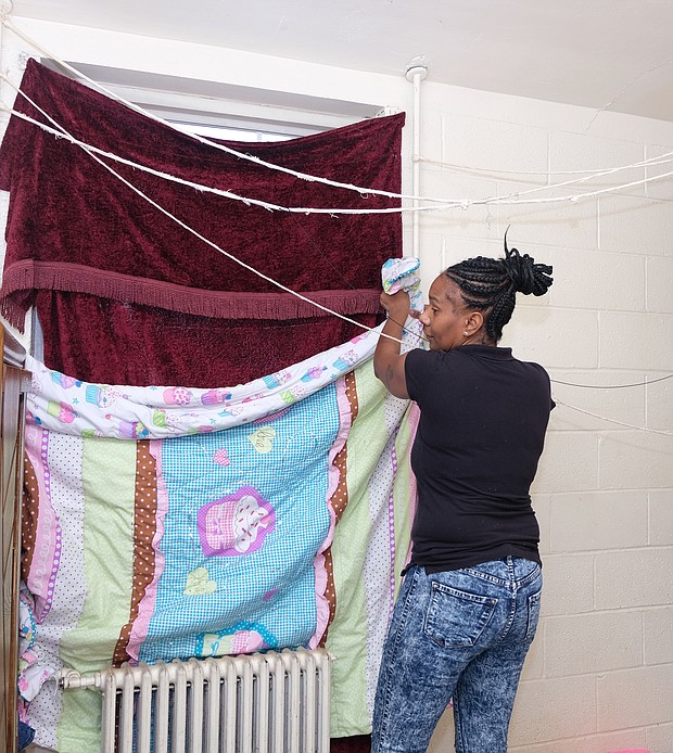 Kanya N. Nash puts blankets and quilts up at the windows to stave off January’s cold in her apartment in the Hillside Court public housing community. She was among hundreds of public housing residents impacted by poor maintenance and the replacement of failed heating systems in buildings run by the Richmond Redevelopment and Housing Authority.