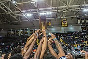 Jubilant John Marshall High School basketball players show off their 3A state championship trophy after their big victory in March over Western Albemarle High School at Virginia Commonwealth University’s Siegel Center. This was the Justices first state championship since 2014.