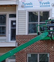 A worker puts siding on the new Artisan Hill apartment building that will have 204 units and underground parking last Saturday. Location: 1000 Carlisle St. (Sandra Sellars/Richmond Free Press)