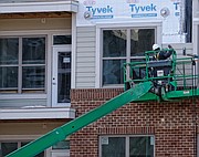 A worker puts siding on the new Artisan Hill apartment building that will have 204 units and underground parking last Saturday. Location: 1000 Carlisle St. (Sandra Sellars/Richmond Free Press)