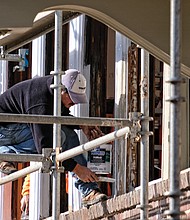 A worker paints windows last Saturday on the former Fulton Elementary School property that is being renovated into 33 apartments in the city’s East End. (Sandra Sellars/Richmond Free Press)