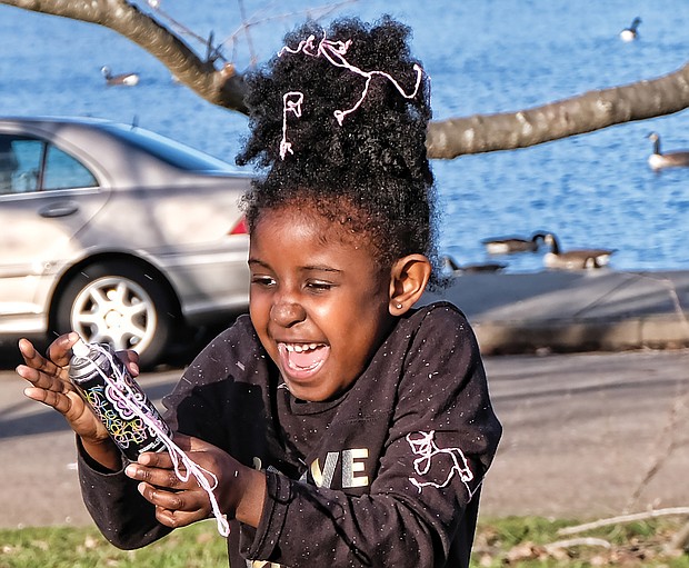 Warming up to winter: Chelsea Garba, 5, gets carried away with a spray can of Goofy String while playing with her dad, Makka Garba, by Fountain Lake in Byrd Park last Saturday, when the day was sunny and temperatures hovered near 60 degrees. What a change this weekend will bring, when high temperatures will be in the 30s, with snow forecast for Sunday. (Sandra Sellars/Richmond Free Press)