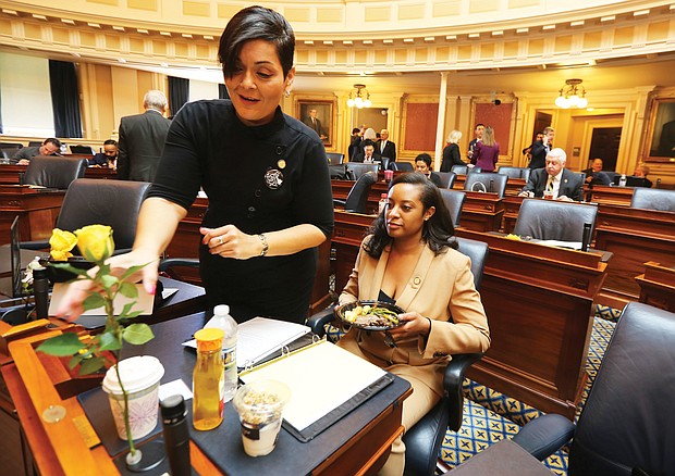 New year, new session: Delegate Hala S. Ayala of Prince William County adjusts a yellow rose — representing support for the ERA — on the desk of a Prince William colleague, Delegate Jennifer D. Carroll Foy. (Regina H. Boone/Richmond Free Press)