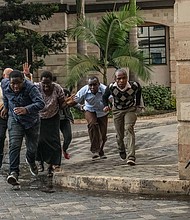People run for cover after being rescued from the Dusit hotel.