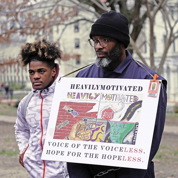 Rallying for prison reform: Hampton residents Wyheem Vessels, left, and Thurston White join more than 200 people who turned out to protest against solitary confinement and other prisoner-related issues at the 2nd Annual Prison Reform Rally at Capitol Square last Saturday. A coalition of advocates, former prisoners and relatives held the event to promote legislation to abolish solitary confinement, cut lengthy sentences and restore parole or the system of early release for model prisoners that was abolished in 1995.  (Sandra Sellars/Richmond Free Press)