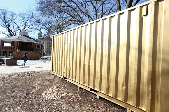 A gold-painted shipping container that can transport you around the world without spending a dime has been placed in Monroe ...