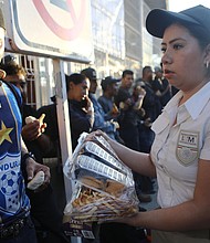 Central American migrants, part of a new 'migrant caravan', are given food by a Mexican immigration official while standing on the international border bridge between Guatemala and Mexico to wait for humanitarian visas on January 18, 2019 in Ciudad Hidalgo, Mexico