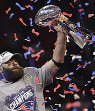 New England Patriot Julian Edelman hoists the Vince Lombardi trophy in the air after the team's Super Bowl win.