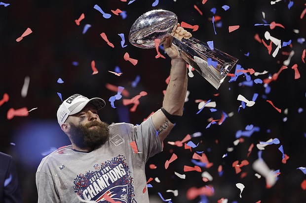 New England Patriot Julian Edelman hoists the Vince Lombardi trophy in the air after the team's Super Bowl win.