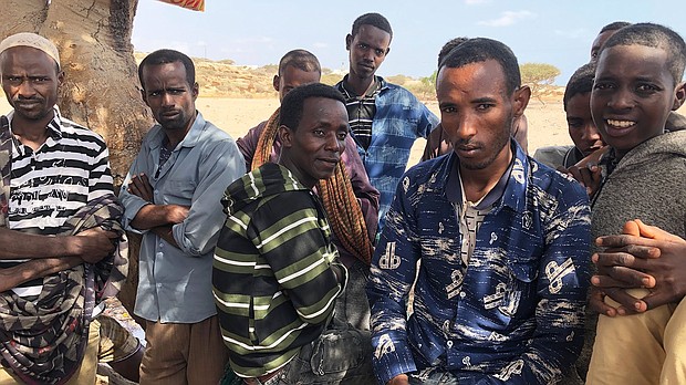 A group of men wait for smugglers to arrive to take them across the Bab al-Mandeb Strait to Yemen.